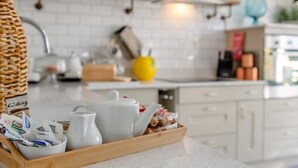 Una cocina con armarios blancos, una bandeja de madera con utensilios de cocina y un jarrón amarillo sobre la encimera.