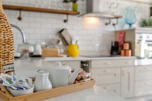 A kitchen with white cabinets, a wooden tray with kitchen items, and a yellow vase on the counter.