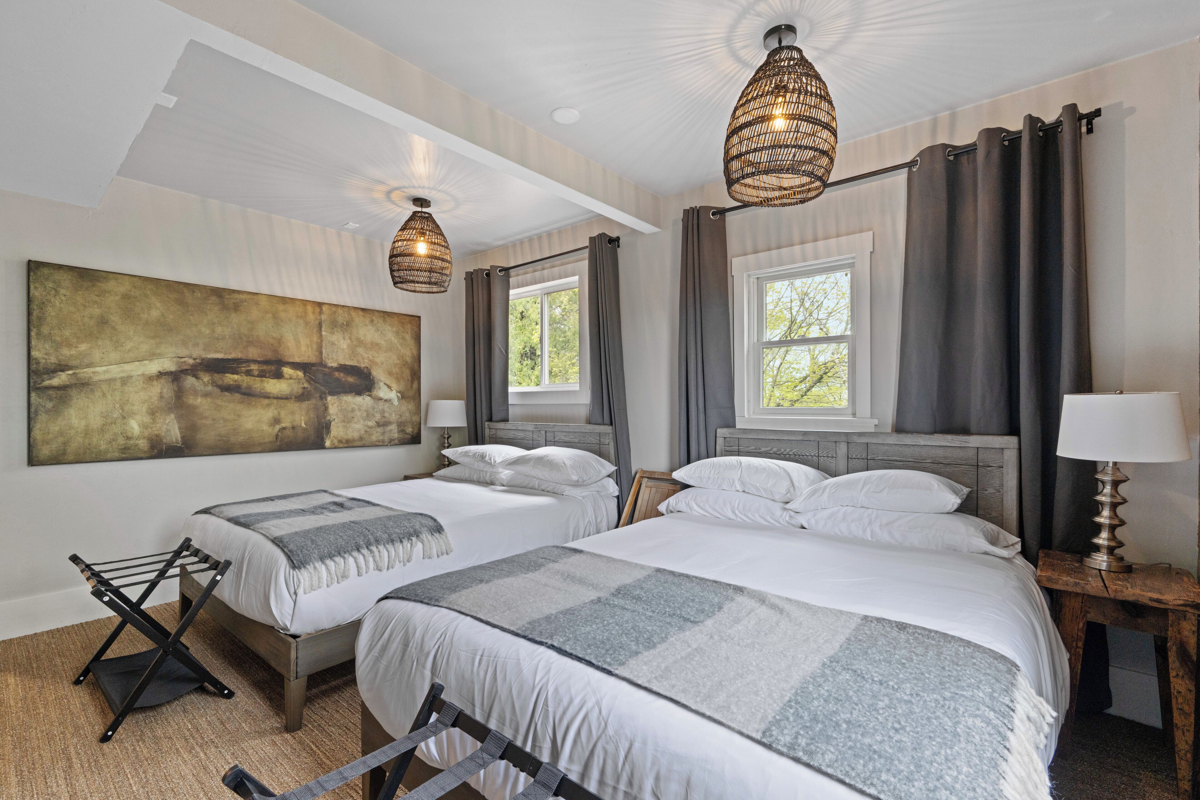 Ein Hotelzimmer mit zwei Betten, einem großen abstrakten Gemälde und einem Fenster mit Vorhängen.