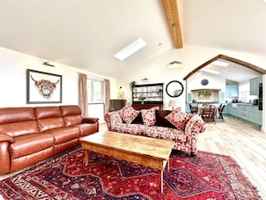 A living room with a brown leather sofa, a patterned sofa, a wooden coffee table, and a red patterned rug. - 2 Bed in Witheridge (oc-b29206) (Witheridge)