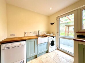 A compact kitchen with a dishwasher, washing machine, and a sink. - 2 Bed in Witheridge (oc-b29206) (Witheridge)