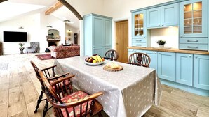 A dining area with a table set for four, surrounded by light blue cabinets and wooden chairs. - 2 Bed in Witheridge (oc-b29206) (Witheridge)