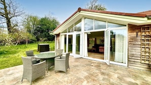 A patio with a table and chairs, a wooden deck, and a glass door leading to an interior space. - 2 Bed in Witheridge (oc-b29206) (Witheridge)