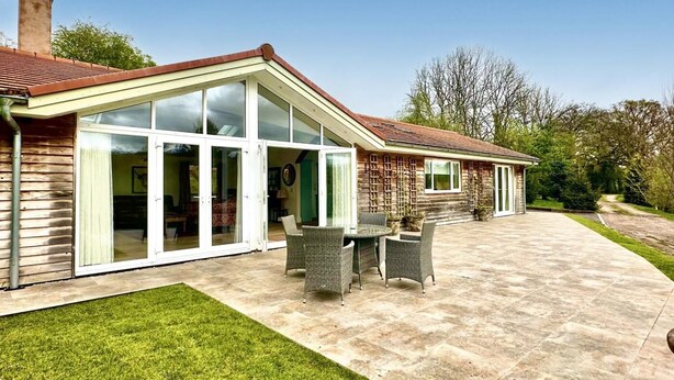A house with a patio area, a dining set, and a large sliding glass door. - 2 Bed in Witheridge (oc-b29206) (Witheridge)
