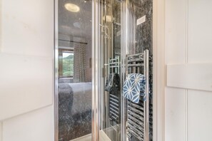 A bathroom with a glass shower enclosure, a marble wall, and a towel rack with patterned towels. - 3 Bed in Withypool (oc-o18550) (Withypool)
