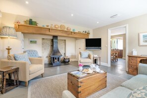 A cozy living room with a stone fireplace, comfortable seating, a flat-screen TV, and a dining area. - 3 Bed in Withypool (oc-o18550) (Withypool)