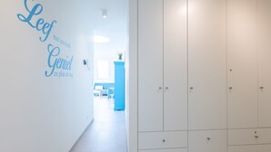 Een gang met een witte kast, een blauwe kast en een muur met tekst.
