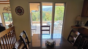 A dining area with a table, chairs, and a view of the outdoors through a sliding glass door. - Bluestone Manor--spacious mountain home for your next adventure (Nimitz)