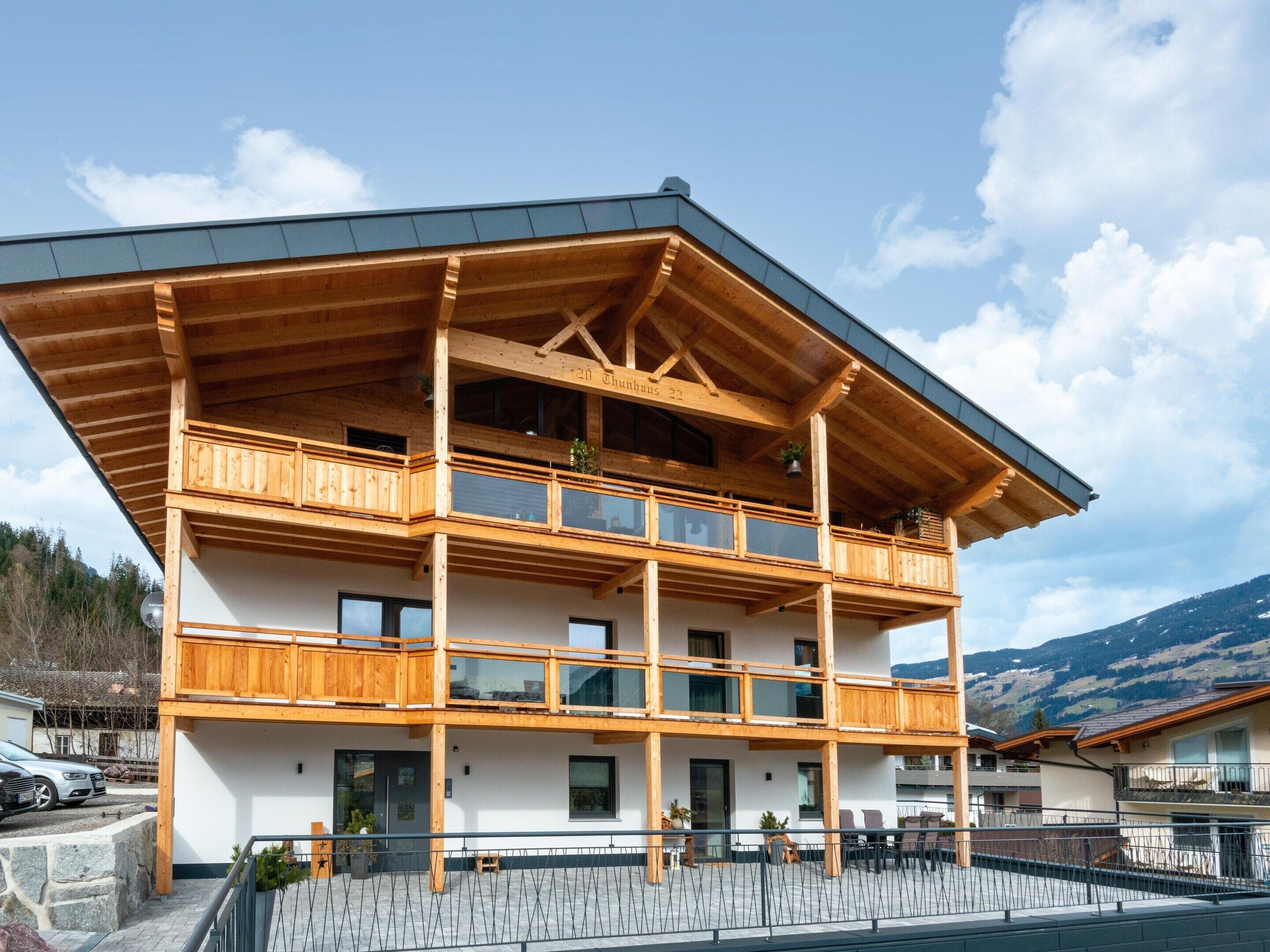 A multi-story wooden building with balconies, large windows, and a stone facade.
