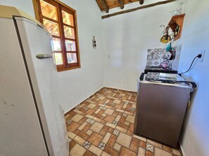 Una cocina pequeña con refrigerador, ventana y piso de baldosas.