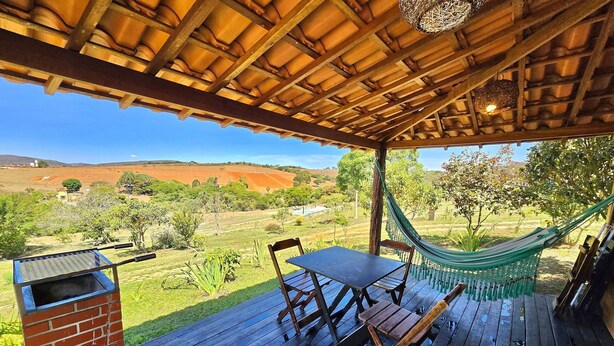 Zona exterior coberta amb taula i cadires, un hamaca i una barbacoa de maó.