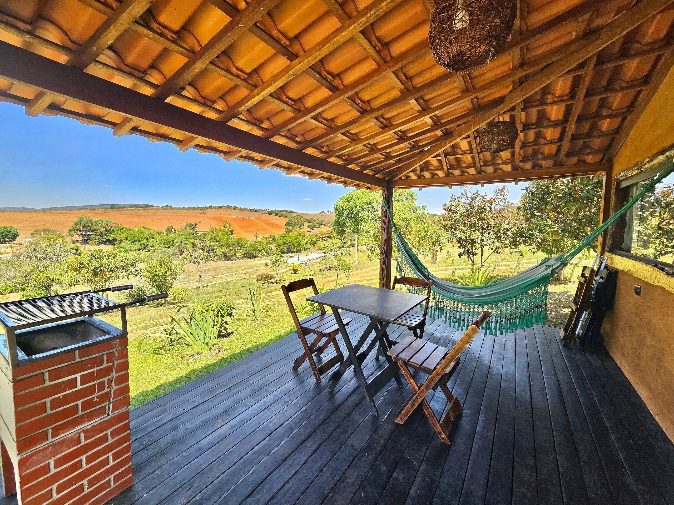 A covered patio with a table and chairs, a hammock, and a brick barbecue.