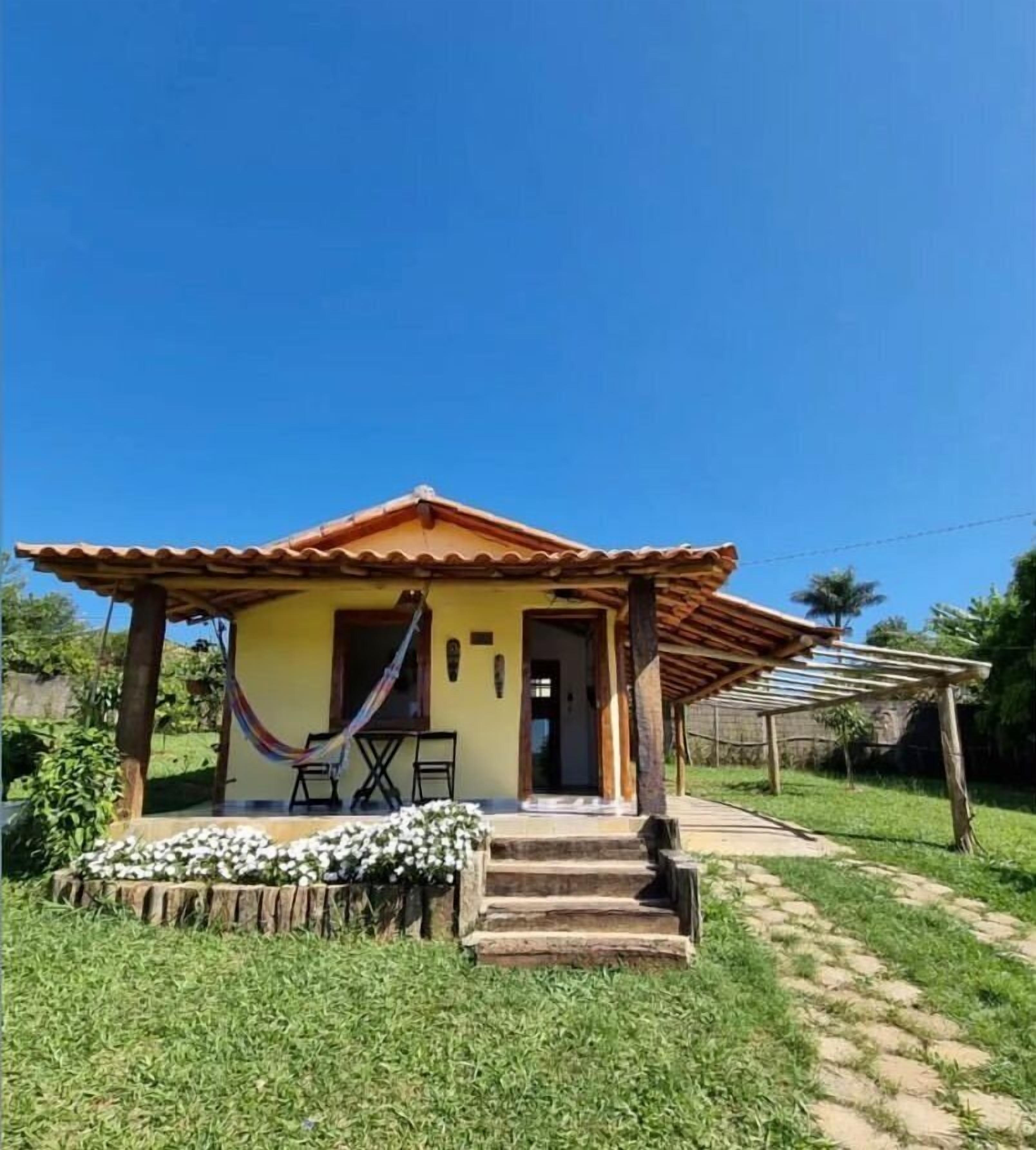 A small house with a tiled roof, a porch with steps, and a hammock.