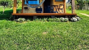 Una casa de dues plantes amb un porxo de fusta, una cadira espanyola i mobles d'exterior.