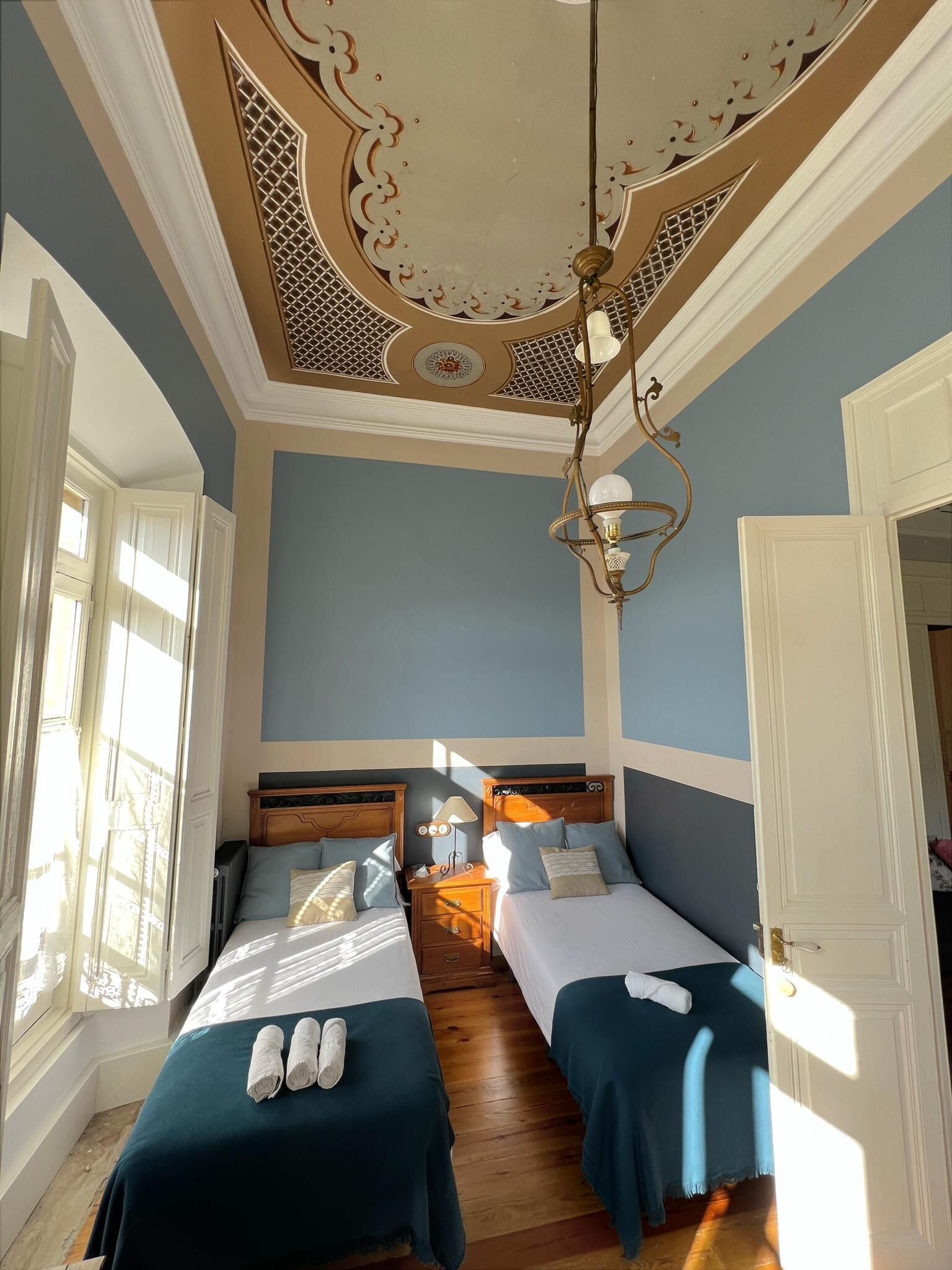 Habitación de hotel con dos camas, un candelabro y vistas a la calle.
