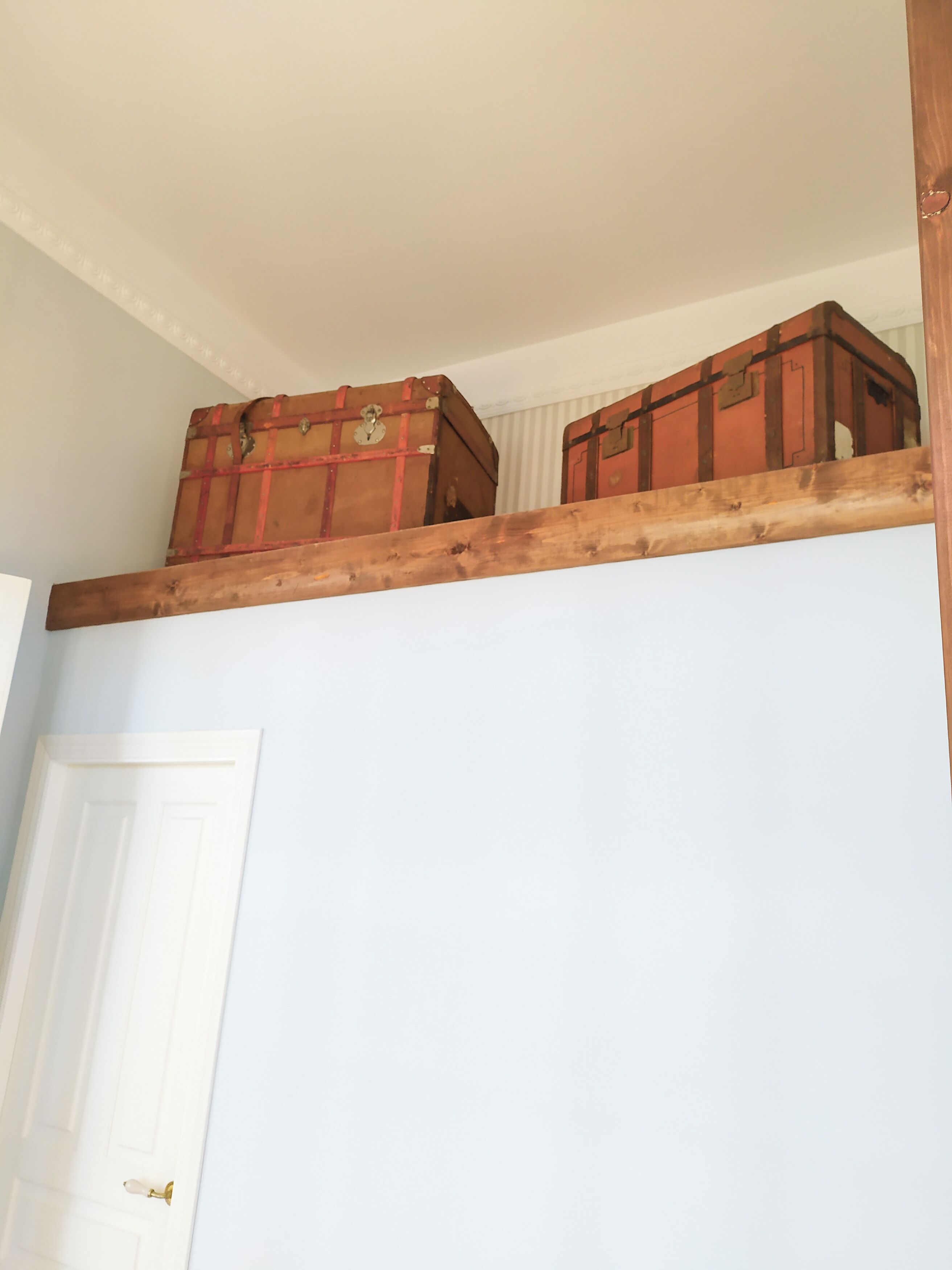 Ein Zimmer mit einer Holzplattform, auf der zwei alte Koffer stehen.