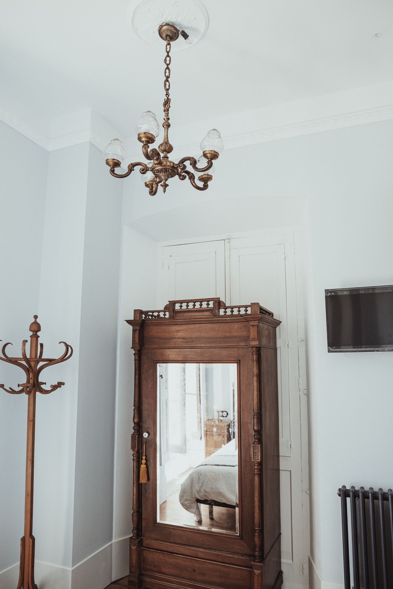 A room with a wooden cabinet, a chandelier, and a radiator.