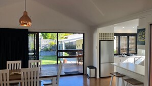 Eine moderne Küche mit integriertem Kühlschrank, einem Essbereich mit Tisch und Stühlen sowie einer Glastür, die in einen Garten führt.