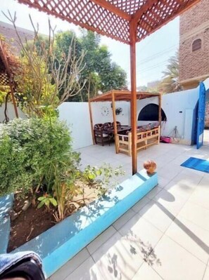 Relax in a serene outdoor space with a pergola, seating area, and lush garden.