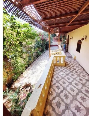 Relax under the pergola, surrounded by lush greenery and a patterned tile floor.