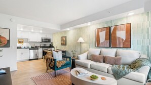 A modern living room with a sofa, coffee table, and a dining area with a chair and table. - Cityside Escape (Branson)