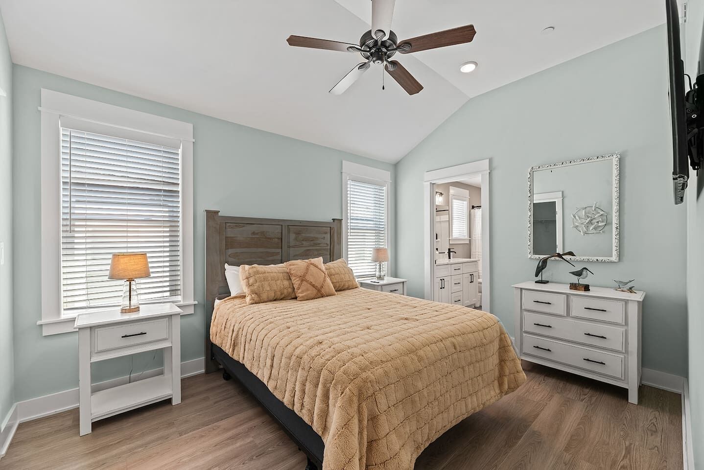 A bedroom with a bed, nightstands, a dresser, a ceiling fan, and a large window with blinds.