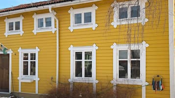 A yellow building with white trim, multiple windows, and a visible hose reel on the side.