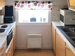 A compact kitchen with a window, a microwave, a stove, and a sink. - 3 Person Holiday Home in Ostersund (Östersund)