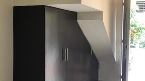 Un interno moderno con un armadio in legno scuro, un soffitto bianco e una porta che dà su uno spazio esterno.