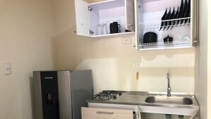 Una cucina compatta con frigorifero, fornello, lavello e pensili.