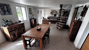 Un comedor amplio con una mesa y sillas de madera, un suelo con estampado de espiga y una escalera que sube a un nivel superior.