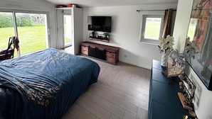 Un dormitorio con cama, televisión, cómoda y ventana.