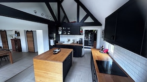 Una cocina moderna con una isla central, armarios negros y un amplio ventanal que proporciona luz natural.