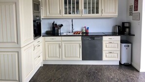 A kitchen with white cabinetry, a stainless steel dishwasher, and a granite countertop. - Schaalseehobbit Modern Retreat (Seedorf)