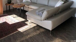 A modern living room with a beige sofa, a small side table, a floor lamp, and a mirror on the wall. - Schaalseehobbit Modern Retreat (Seedorf)