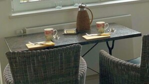 A room with a view of a lake, a table with chairs, a kettle, and a mug. - Schaalseehobbit Modern Retreat (Seedorf)