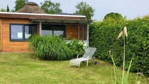 A modern house with a wooden exterior, a glass door, and a small garden with a lawn chair. - Schaalseehobbit Modern Retreat (Seedorf)