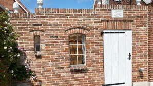 A brick building with a white door and a window with a white frame. - Cosy Holiday Home Near the Centre (Krummhoern)