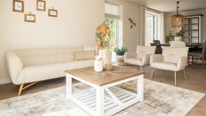 A living room with a sofa, chairs, a coffee table, and a dining area with a table and chairs.