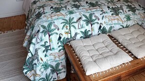A bed with a patterned bedspread, a yellow throw pillow, and two bedside lamps.