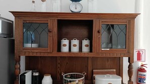 A wooden cabinet with glass doors, containing kitchenware and a scale.