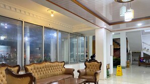 A lobby with leather sofas, a coffee table, large windows, and a tiled floor. - New Wijaya Hotel (Kalasan)