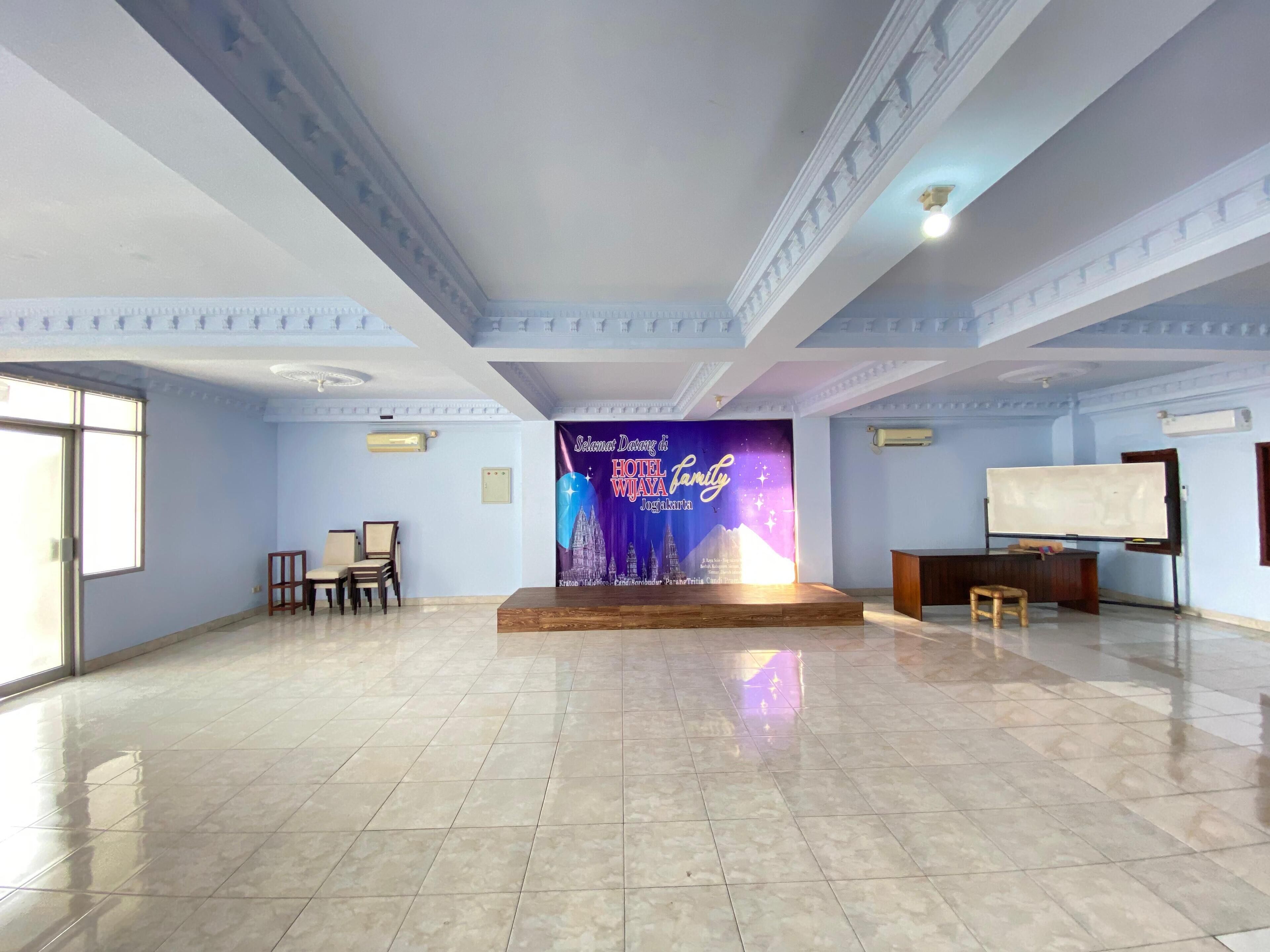 Un hall d’hôtel spacieux, doté d’une scène, d’un espace salon et d’une grande banderole.