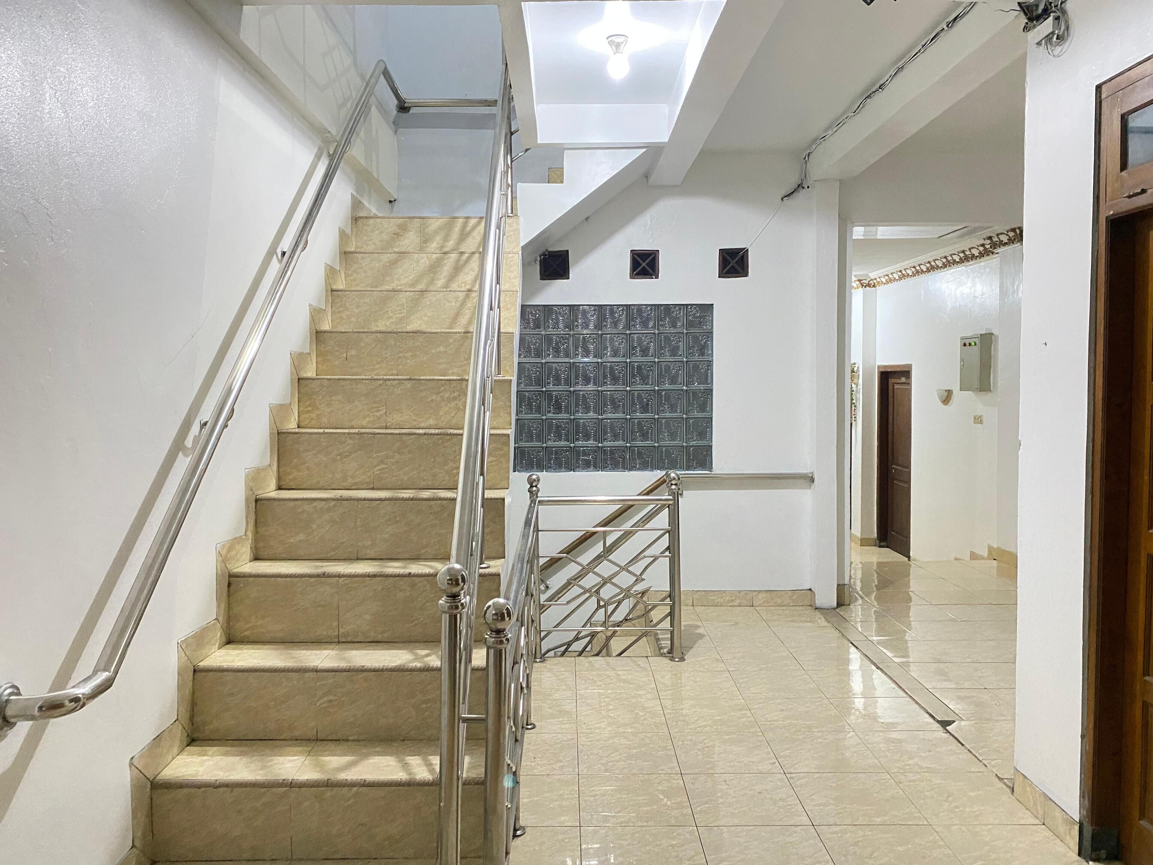 A staircase with a metal railing, a tiled floor, and a skylight above.