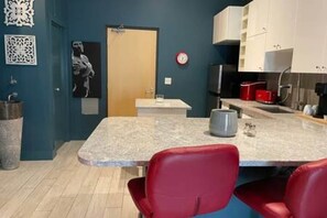 Une cuisine moderne avec un plan de travail en granit, des chaises rouges et un petit îlot central.