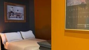 Une chambre d’hôtel avec un lit, un tableau encadré au mur et une affiche.