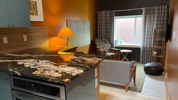 Une cuisine dotée d’un plan de travail en granit, d’une cuisinière et d’un coin repas avec une chaise et une table.