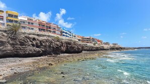A coastal hotel with colorful buildings, clear blue waters, and rocky terrain.
