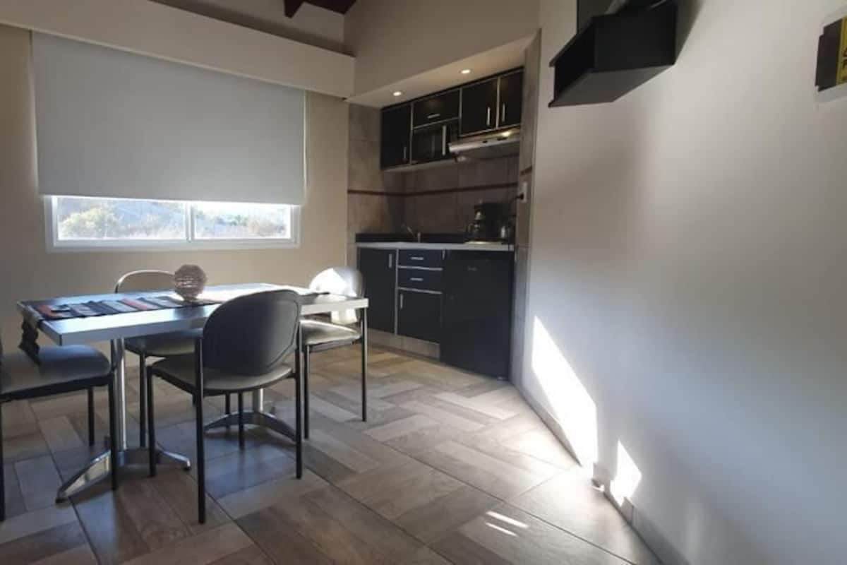 A modern kitchen with dark cabinets, a countertop, and a window.
