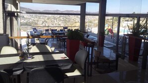 A restaurant with tables and chairs, a view of mountains, and a sign that says "PEACE". - ERNESTINA VILLAGE (Villa Carlos Paz)